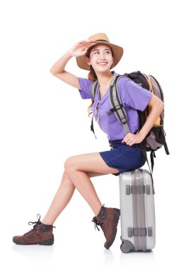 Beyaz arka plan üzerinde sırt çantası ile bavul üzerinde oturan kadın Gezgin