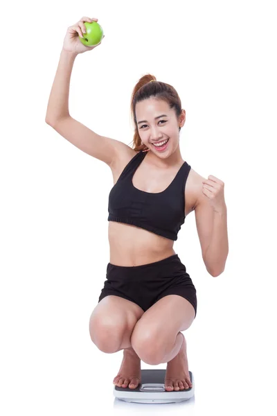Women on scale cheering for achieving her weight loss goal and green apple. — Stock Photo, Image