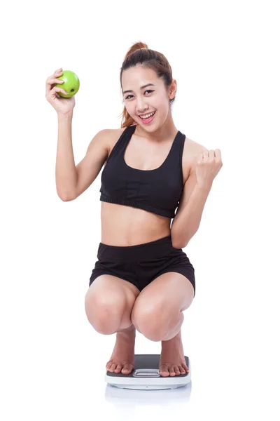 Women on scale cheering for achieving her weight loss goal and green apple. — Stock Photo, Image