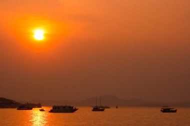 Balıkçı teknesi üzerinde gündoğumu silüeti.