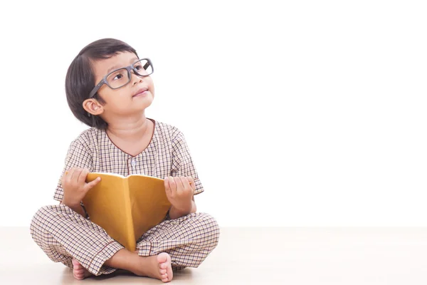 Netter Junge liest ein Buch, während er eine Brille trägt — Stockfoto