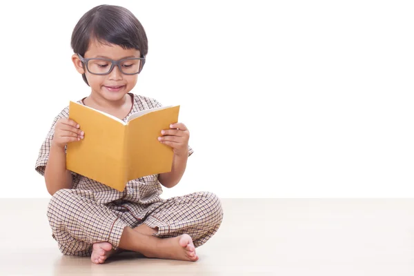 Rapaz bonito está lendo um livro enquanto usa óculos — Fotografia de Stock