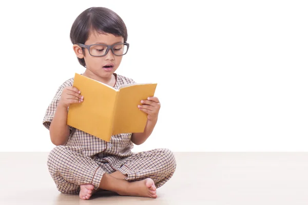 Netter Junge liest ein Buch, während er eine Brille trägt — Stockfoto