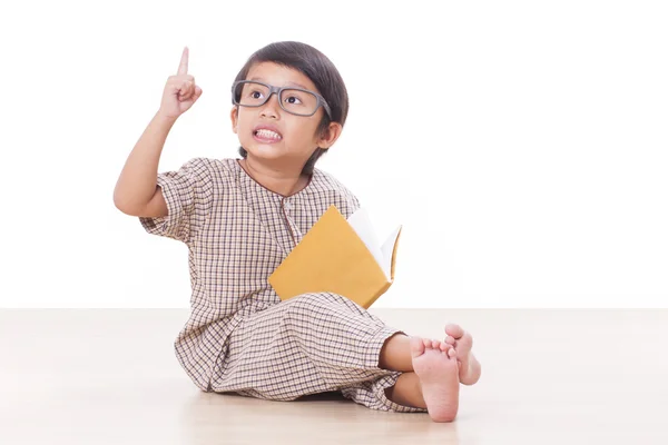 Söt pojke läser en bok medan bär glasögon — Stockfoto