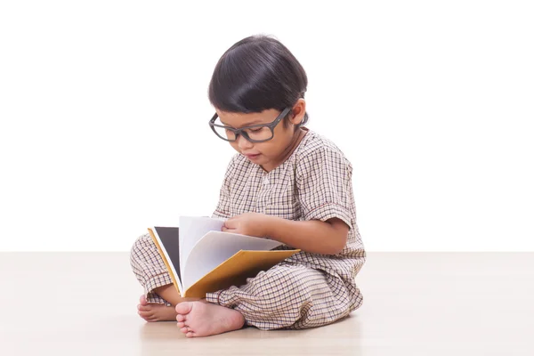 Söt pojke läser en bok medan bär glasögon — Stockfoto