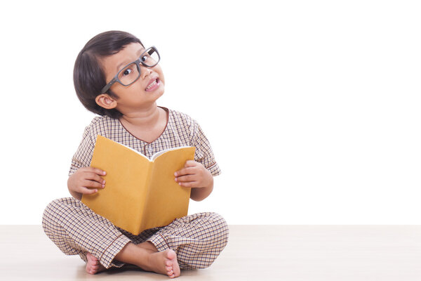 Милый мальчик читает книгу в очках
