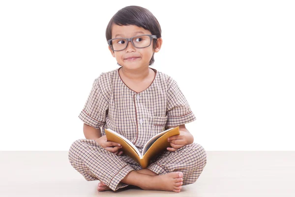 Χαριτωμένο αγόρι διαβάζει ένα βιβλίο ενώ φορώντας γυαλιά — Φωτογραφία Αρχείου