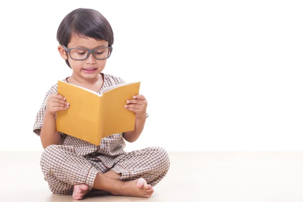 Carino ragazzo sta leggendo un libro mentre indossa occhiali — Foto Stock