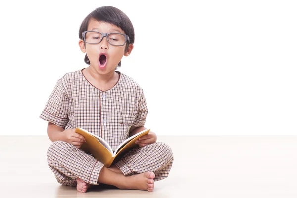 Söt pojke läser en bok medan bär glasögon — Stockfoto