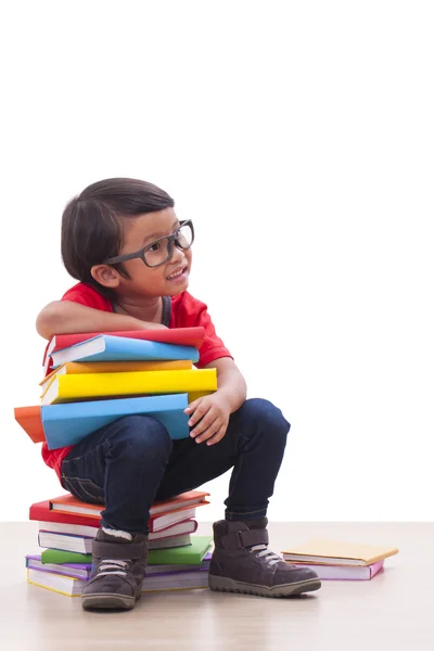 Glücklicher Junge sitzt und Bücher in der Hand hält — Stockfoto