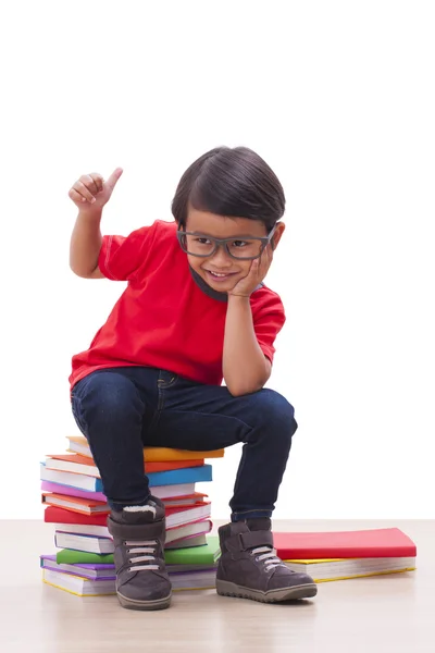 Симпатичный мальчик сидит на книгах — стоковое фото