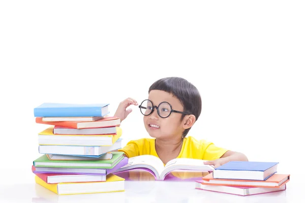 Menino bonito está lendo um livro enquanto usa óculos . — Fotografia de Stock