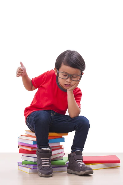 Милый мальчик сидит на книгах — стоковое фото