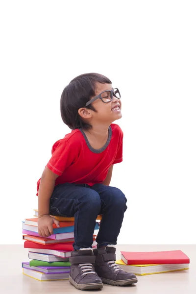 Bonito menino sentado em livros — Fotografia de Stock