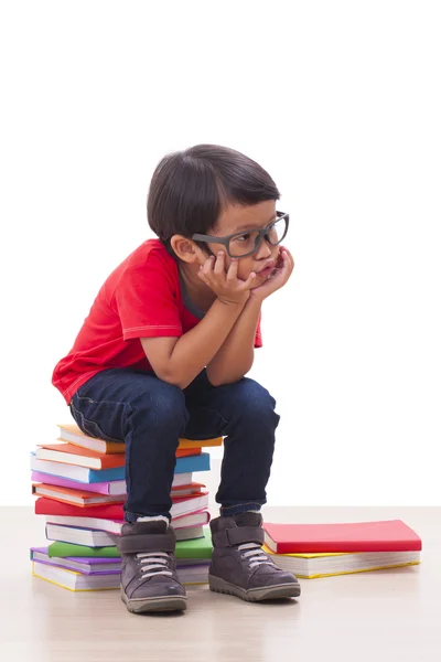 Bonito menino sentado em livros — Fotografia de Stock