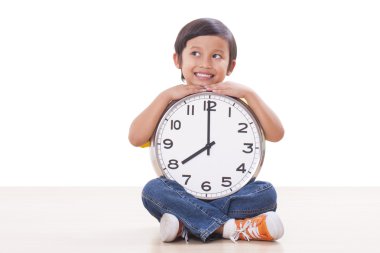 Oturma ve büyük saat tutan şirin çocuk