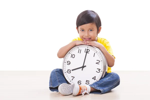 Niedlicher Junge sitzt und hält große Uhr — Stockfoto