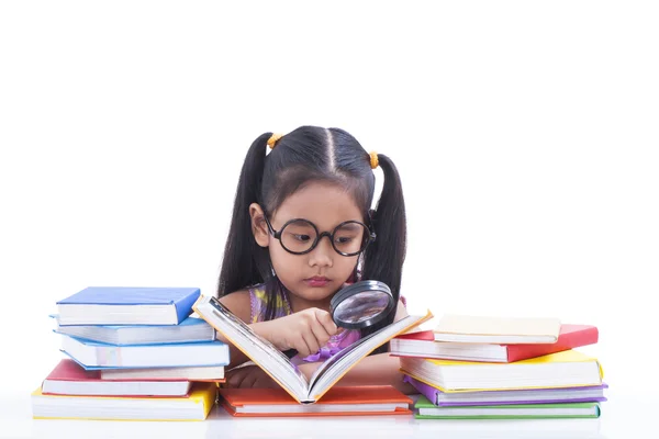 Little girl is reading book and using magnifier. — Stock Photo, Image