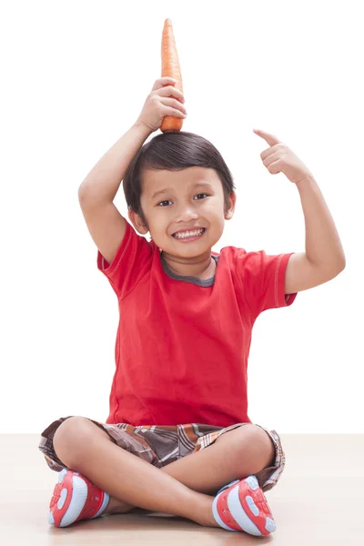 Gelukkige jongen met een wortel. Gezonde voeding concept. — Stockfoto