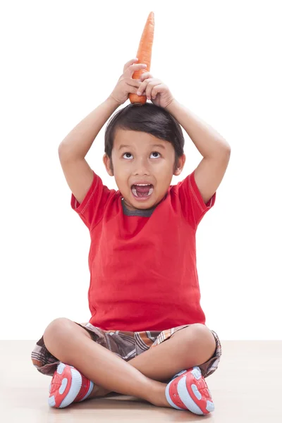 Gelukkige jongen met een wortel. Gezonde voeding concept. — Stockfoto