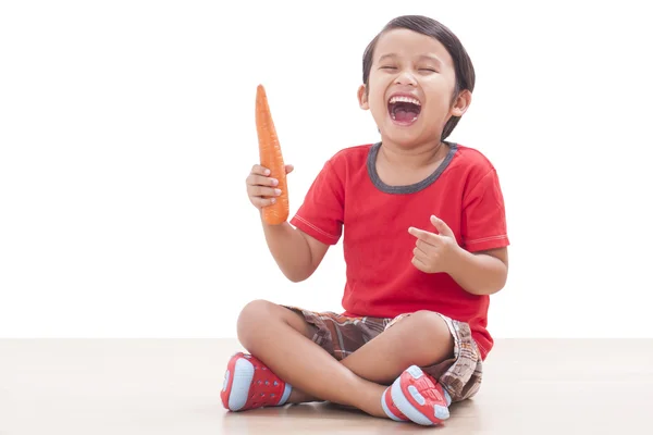 Gelukkige jongen met een wortel. Gezonde voeding concept. — Stockfoto