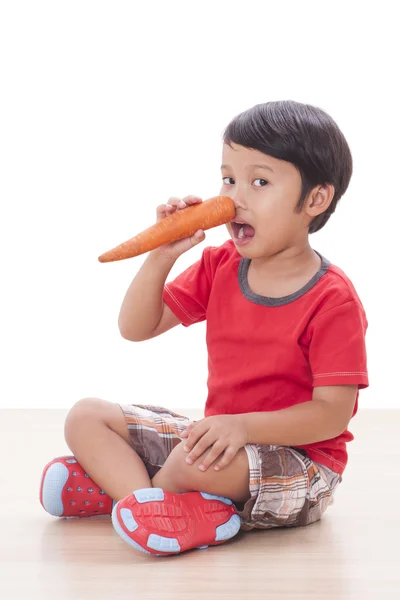 Gelukkige jongen met een wortel. Gezonde voeding concept. — Stockfoto