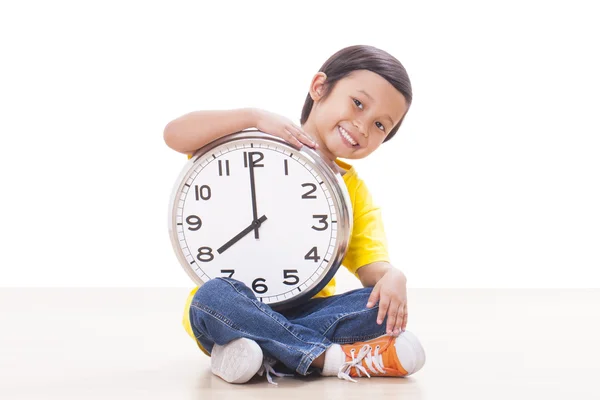 Ładny chłopak siedzi i trzymając wielki zegar — Zdjęcie stockowe