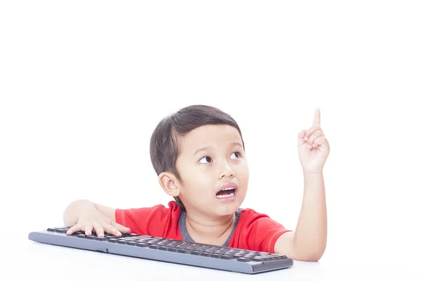 Ładny chłopak przy użyciu klawiatury i wskazujący w górę — Zdjęcie stockowe