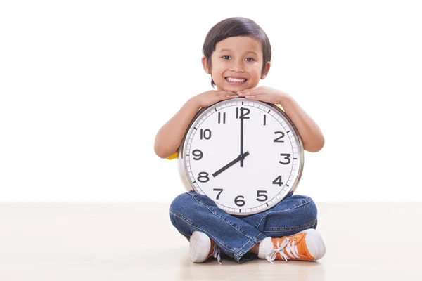 Cute boy sitting and holding big clock Stock Picture