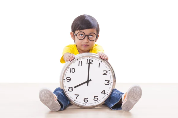 Симпатичный мальчик сидит и держит большие часы — стоковое фото