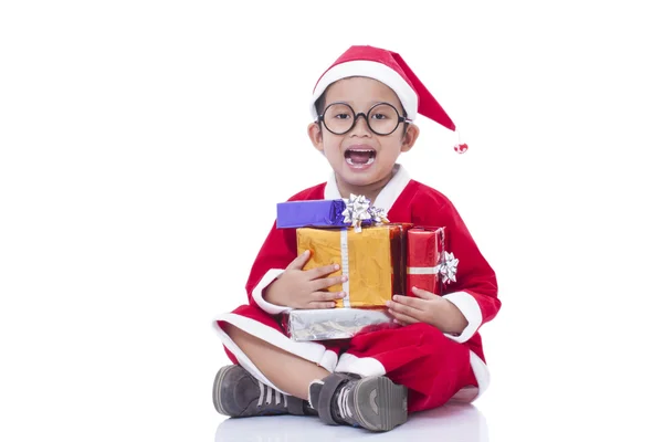 Little boy wearing Santa Claus uniform with gifts — Stock Photo, Image