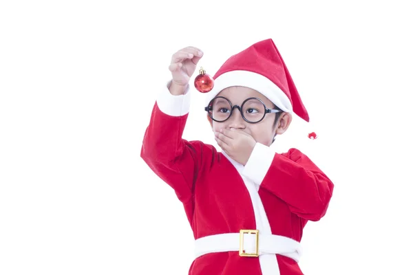 Gelukkige jongen dragen santa claus uniform en houden van rode Kerstmis bal — Stockfoto