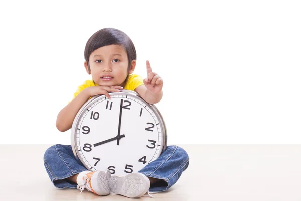 Симпатичный мальчик сидит и держит большие часы — стоковое фото