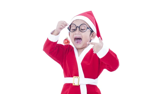 Gelukkige jongen dragen santa claus uniform en houden van rode Kerstmis bal — Stockfoto