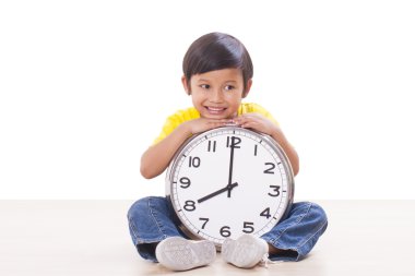 Oturma ve büyük saat tutan şirin çocuk