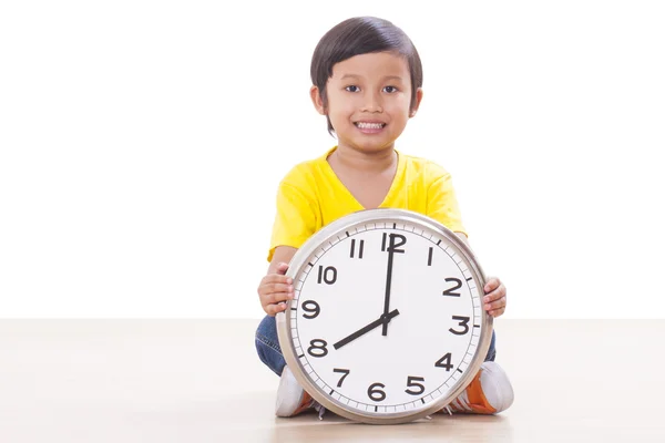 Niedlicher Junge sitzt und hält große Uhr — Stockfoto