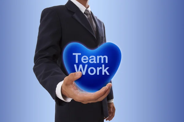 Podnikatel ruka drží modré srdce bublina s týmovou práci slovo — Stock fotografie