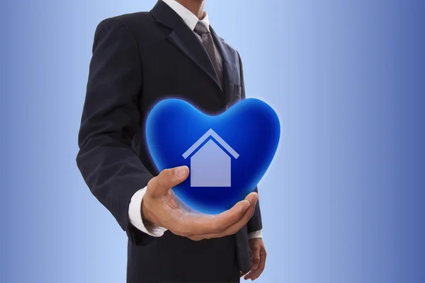 ホームサインと青いハート気泡を持っているビジネスマン手 — ストック写真