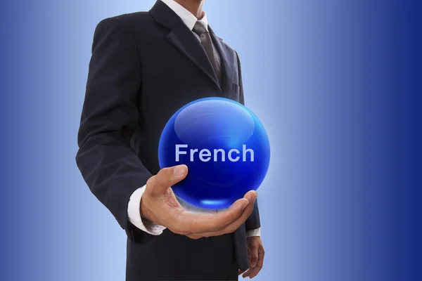 Businessman hand holding blue crystal ball with french word. — Stock Photo, Image