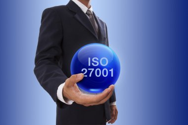 ISO 27001 kelime ile mavi kristal top tutan işadamı el.