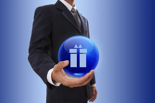 Деловой человек держит в руке синий хрустальный шар с символом подарка . — стоковое фото