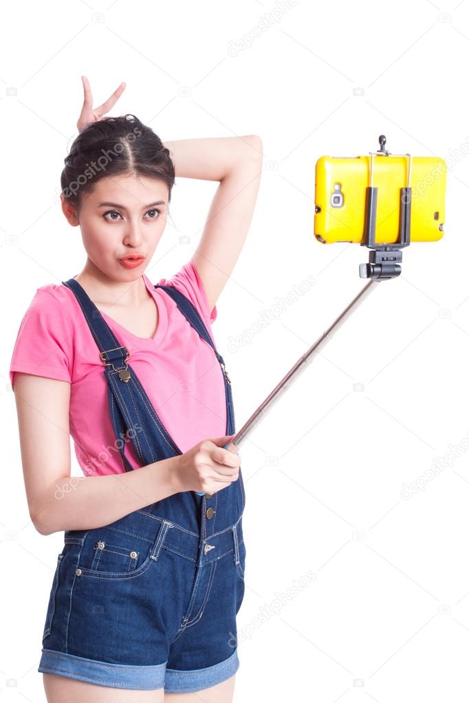 Happy woman taking picture with smartphone selfie stick