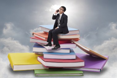 Yığın kitap üzerinde oturan işadamı