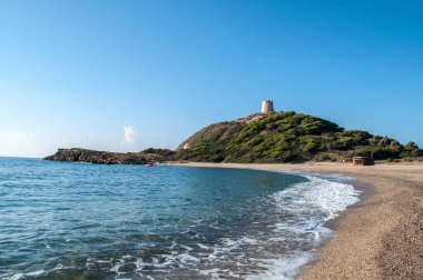 Dağlardaki kumsal ve arkadaki eski kule.