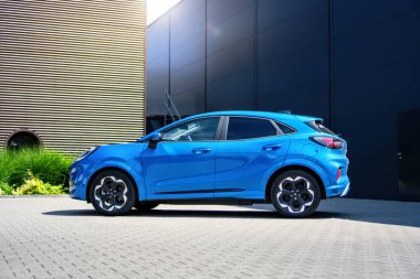Brno, Çek Cumhuriyeti - 18 Haziran 2025: Elektrikli motorlu mavi şehir SUV Ford Puma gen-e. Ekolojik sürüş için batarya ile küçük bir kesişme. Araba endüstriyel bir salonda park halinde..