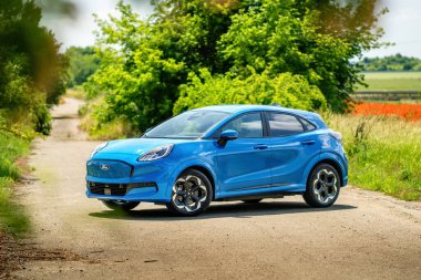 Brno, Çek Cumhuriyeti - 18 Haziran 2025: Elektrikli motorlu mavi şehir SUV Ford Puma gen-e. Ekolojik sürüş için batarya ile küçük bir kesişme. Araba doğada park halinde..