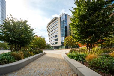 Şehirdeki ofis yönetim binaları. Bir iş parkında modern mimari. Yeşil ve ağaçlarla çevrili yaya geçidi..