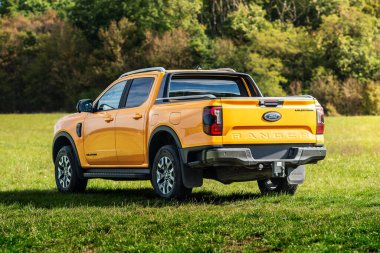 Brno, Çek Cumhuriyeti - 22 Eylül 2025: Sarı Ford Ranger Wildtrack PHEV off-road kamyonet. Büyük bir off-road hibrit araba kırsal alanda bir çayırda duruyor..
