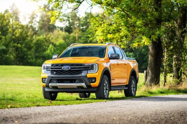 Brno, Çek Cumhuriyeti - 22 Eylül 2025: Sarı Ford Ranger Wildtrack PHEV off-road kamyonet. Doğada, bir çayırın yanında park halinde büyük bir araba çalışıyor..