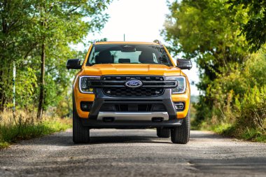 Brno, Çek Cumhuriyeti - 22 Eylül 2025: Sarı Ford Ranger Wildtrack PHEV off-road kamyonet. Ormanın etrafındaki yolda büyük bir araba sürüyorum..